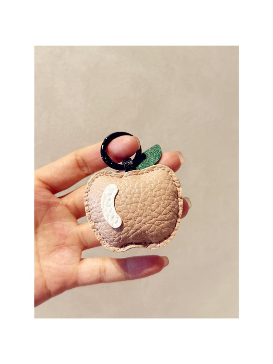Apple keychain held in hand showing compact size and smooth finish