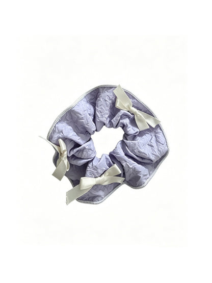 Gifty scrunchie with red ribbon bow displayed on a wooden surface