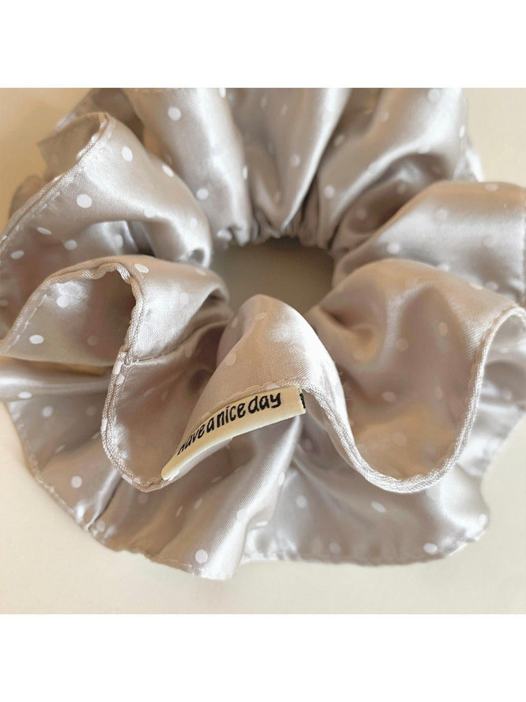 Gifty satin scrunchie styled on a wrist with visible polka dot pattern