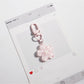 Flower keychain attached to a purse strap with a blurred background