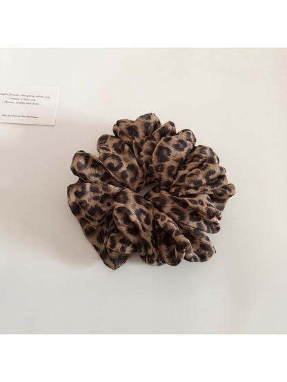 Vintage style leopard print scrunchie placed next to matching hair accessories