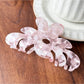 Beau flower shaped claw clip displayed on a flat surface with petals spread