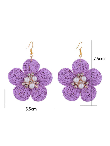 Pair of raffia flower-shaped earrings displayed on a white background showing woven texture