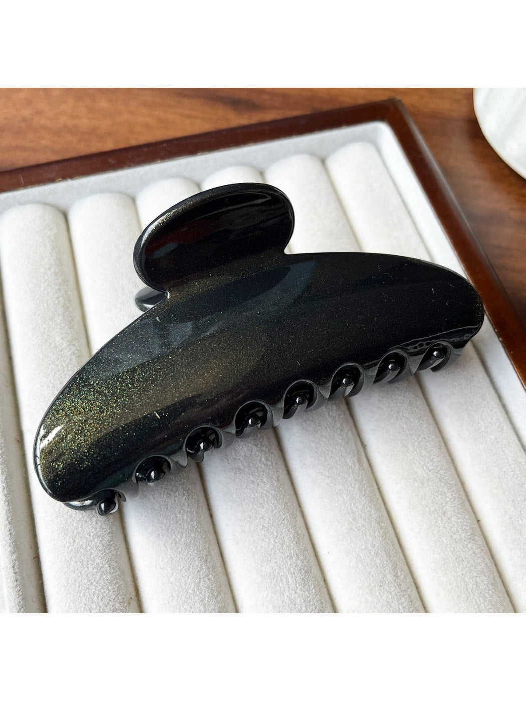Beau hair clip placed on wooden surface with soft shadows
