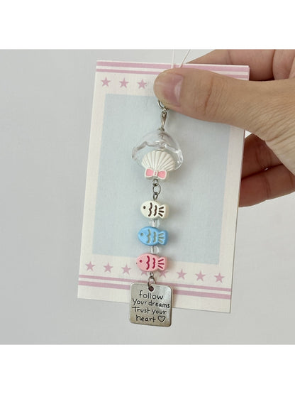 Pastel pink fish-shaped keychain held in hand showing size and texture