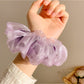Model wearing a solid color ruched scrunchie in her hair, showing its size and fit