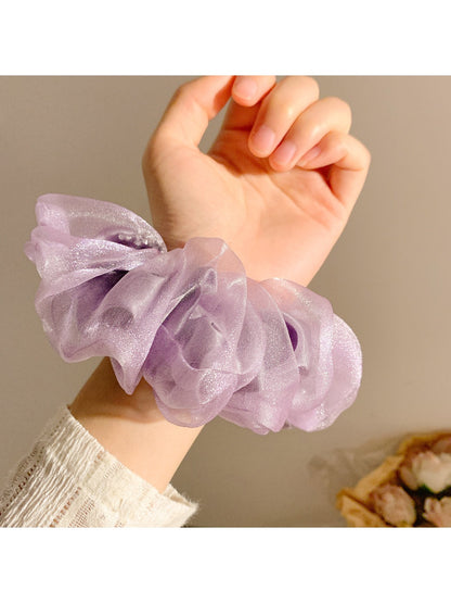 Model wearing a solid color ruched scrunchie in her hair, showing its size and fit