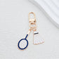 Badminton shuttlecock keychain attached to a silver keyring on a wooden surface