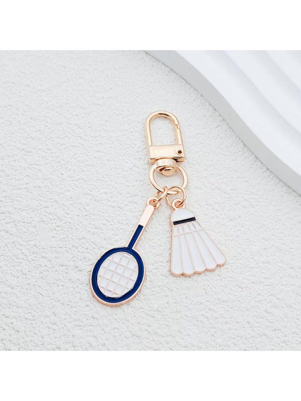 Badminton shuttlecock keychain attached to a silver keyring on a wooden surface