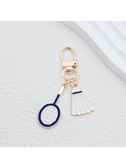 Badminton shuttlecock keychain attached to a silver keyring on a wooden surface