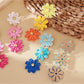 Pair of vibrant flower shaped drop earrings displayed on a white background